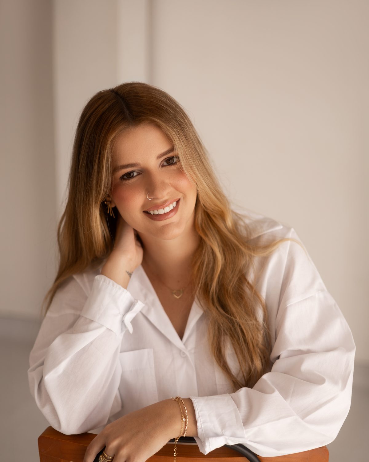 Retrato de Lara Pansiere, psicóloga clínica, apoiada no encosto de uma cadeira de palhinha